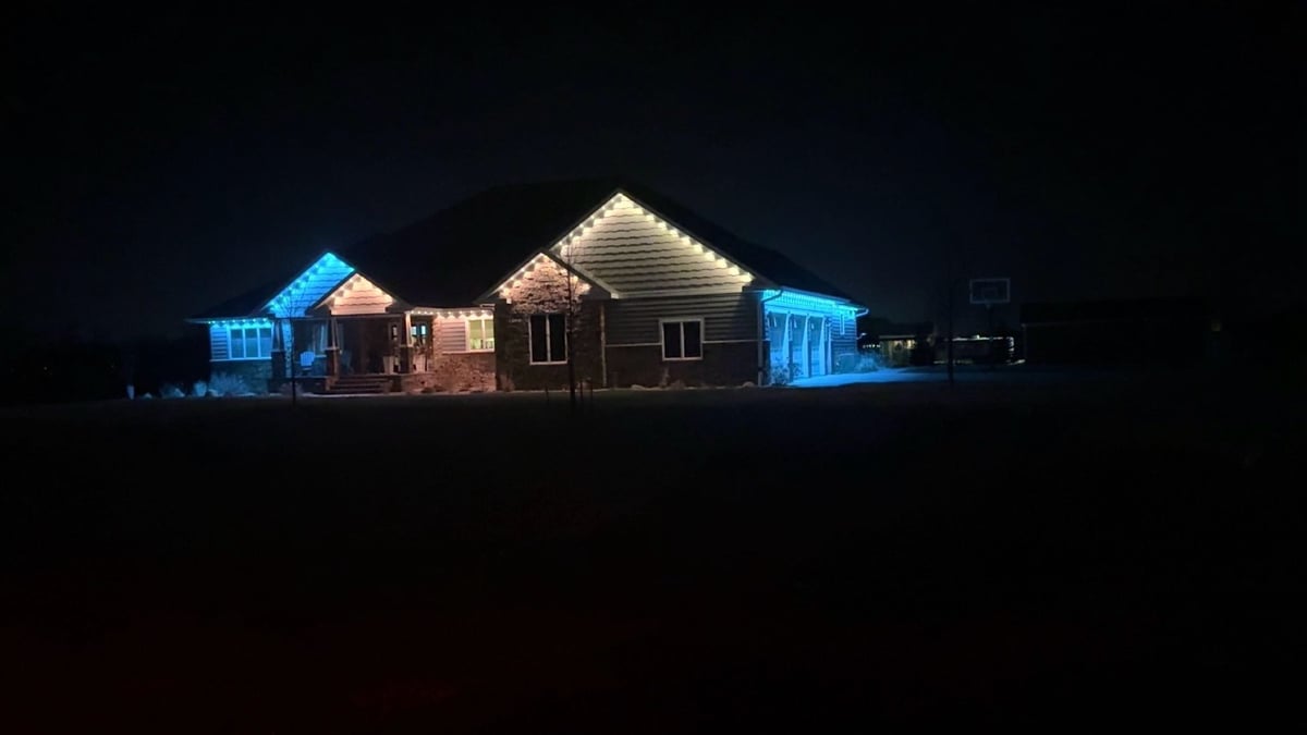 Illuminated beach huts with blue and warm white lights against a dark night sky